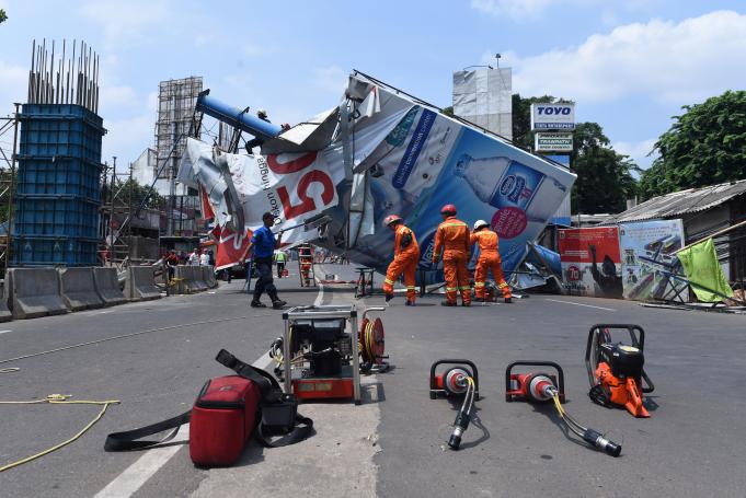 Petugas pemadam kebakaran berusaha mengevakuasi papan reklame yang roboh di Jalan Tendean, Jakarta, Jumat (1/1).