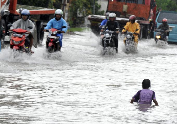 Pengendara berusaha menerobos genangan air di Kelurahan Ujung Pandang Baru, Kecamatan Tallo, Makassar, Sulawesi Selatan, Sabtu (27/2).