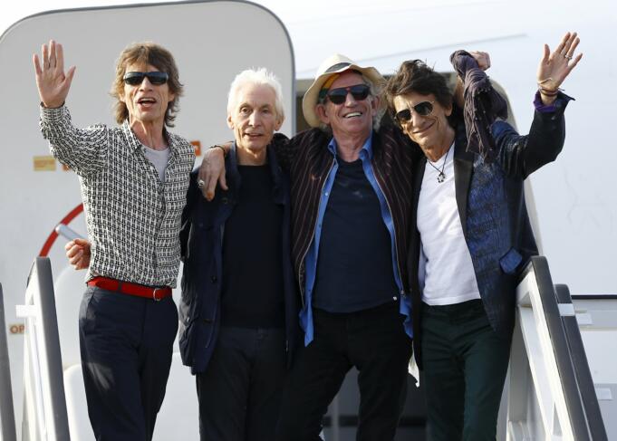 Jagger, Watts, Richards and Wood of the Rolling Stones wave after landing in Havana