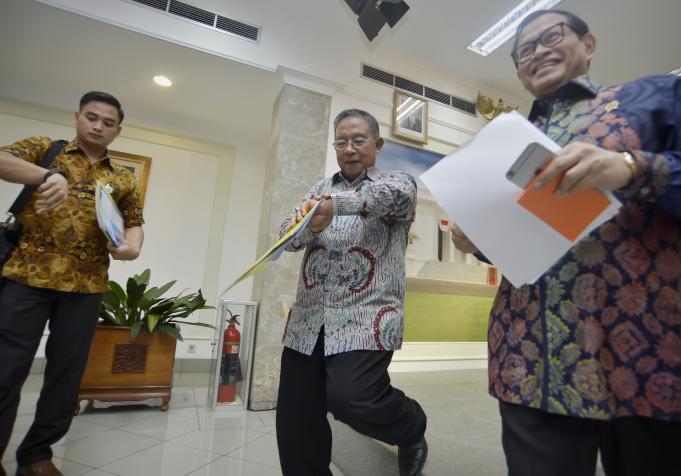 Menko Perekonomian Darmin Nasution (tengah) didampingi Sekretaris Kabinet Pramono Anung (kanan) mengamati jam usai memaparkan Paket Kebijakan Ekonomi Tahap XI di Kantor Presiden, Jakarta, Selasa (29/3).