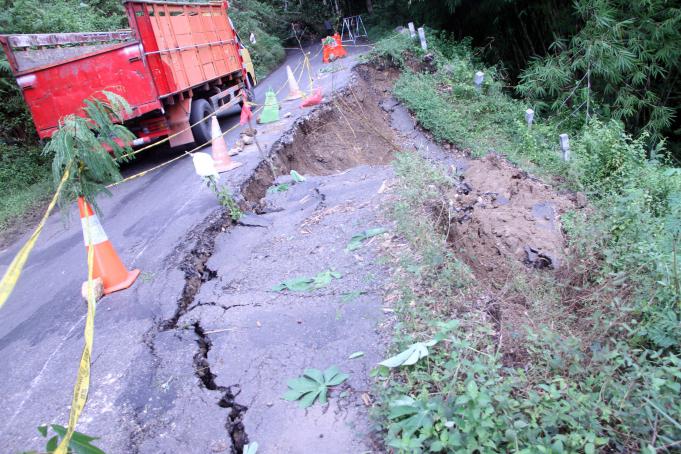 Truk melintas di sisi jalan arteri yang ambrol terseret longsor di Desa Gamping, Trenggalek, Jawa Timur, Selasa (10/5)