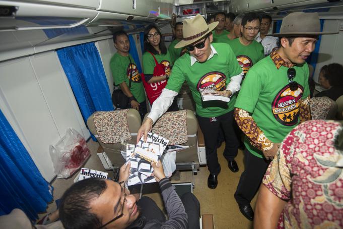 Dua Wakil Ketua KPK Saut Situmorang (tengah) dan Alexander Marwata (kanan) membagikan buku kepada penumpang kereta api dalam sosialisasi antikorupsi bertajuk Ngamen Bareng Antikorupsi di Stasiun Gambir, Jakarta Pusat, Jumat (13/5).