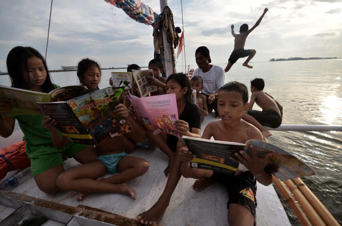 Anak-anak bermain sambil membaca buku di atas Perahu Pustaka Pattingalloang saat sandar di pantai Losari