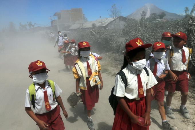 Sejumlah siswa SD melintas di jalan yang dipenuhi debu vulkanik erupsi Gunung Sinabung seusai bersekolah di Desa Gajah, Karo, Sumatera Utara, Senin (23/5).