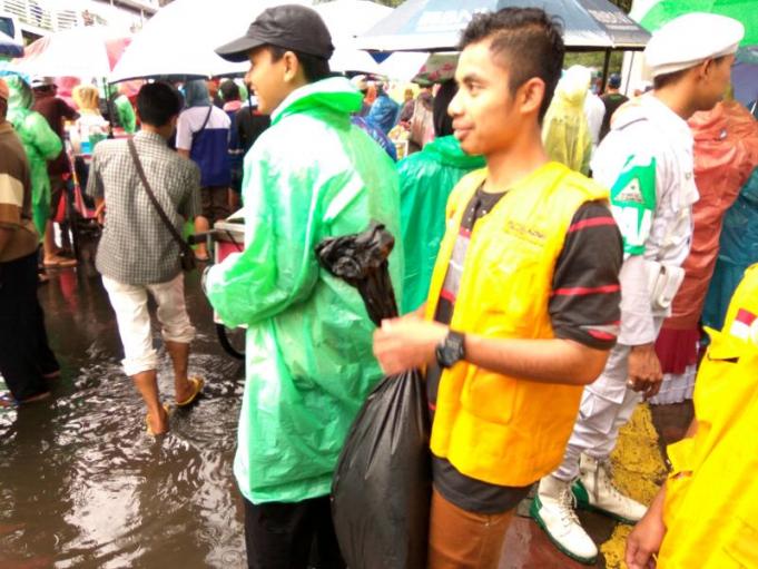 Di Tengah Guyuran Hujan, Pasukan Berompi Kuning Ini Tampak Serius Membersihkan Sampah