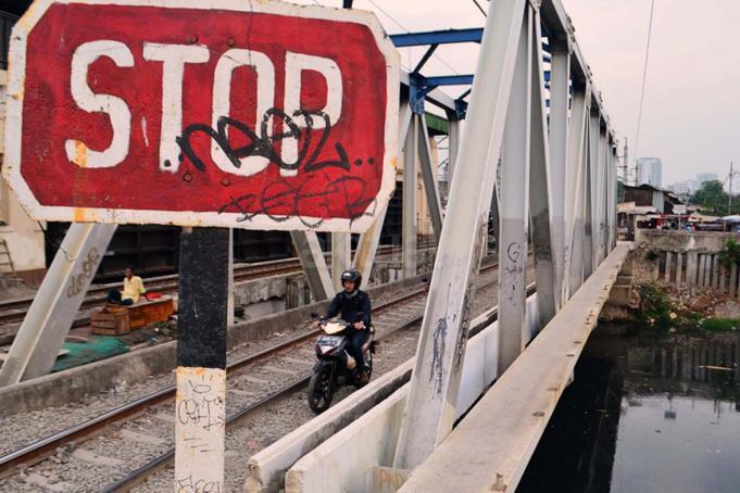 Minimnya sarana penyeberangan jalan di kawasan tersebut, membuat warga harus melintasi jalan setapak di pintu air aliran Kanal Banjir Barat (KBB) Petamburan sebagai jalur alternatif. AKTUAL/Munzir