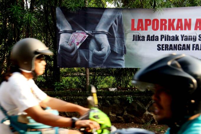 Pengendara motor melintas didepan Spanduk yang bertuliskan " Laporkan Aparat Jika Ada Pihak Yang Sebar Uang Serangan Fajar" di Jalan Menteng Atas, Jakarta, Selasa (14/2/2017). Spanduk penolakan Serangan Fajar yang mengatasmakan Koalisi Jakarta Majoe mengajak masyarakat Jakarta untuk tidak menerima uang dalam Pilkada DKI (15/2/2017). AKTUAL/Munzir