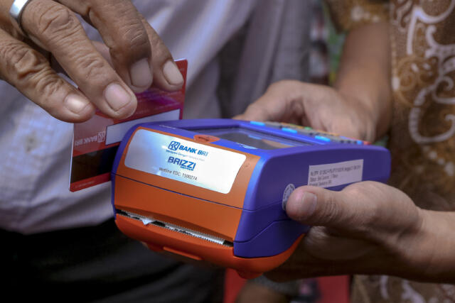 Petugas Rumah Pangan Kita (RPK) Kota Batam, menunjukkan cara pembayaran non tunai menggunakan Kartu Keluarga Sejahtera (KKS) yang didukung Bank BRI melalui BRIlink, untuk mendapatkan bantuan sembako dari pemerintah di Batam, Kepulauan Riau, Kamis (23/2).