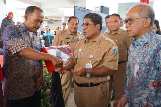 Plt Gubernur DKI Jakarta,Soni Sumarsono (tengah) didampingi Direktur Utama Bank DKI, Kresno Sediarsi (kanan), Walikota Jakarta Barat, Anas Effendie (kiri) serta Kepala Dinas Perumahan DKI, Arifin menyerahkan kartu Jakarta One untuk penghuni rusun Pesakih, Kalideres, Jakarta Barat seusai peresmiaan pengunaannya Senin (6/2). Pengunaaan abesensi elektronik lingkungan rumah susun yang telah mulai diimplementasikan sejak Agustus 2016 lalu, Hingga saat ini sudah sebanyak 9.459 penghuni atau 70% dari total 13.731 penghuni rumah susun yang telah memiliki kartu jakarta one (kartu rusun) di 23 rumah susun milik Pemprov DKI Jakarta. Absensi elektronik digunakan sebagai media otensifikasi atau pengecekan dan absensi penghuni rusun secara berkala sesuai dengan ketentuan dari Dinas Perumahan. AKTUAL/Eko S Hilman