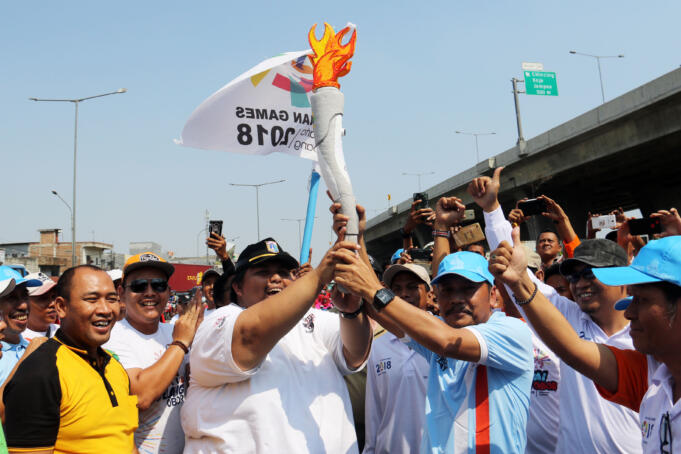 Pawai replika obor Asean Games 2018 di kelurahan Kalibaru Kecamatan Cilincing Jakarta Utara, Minggu, (15/7). AKTUAL/WARNOTO