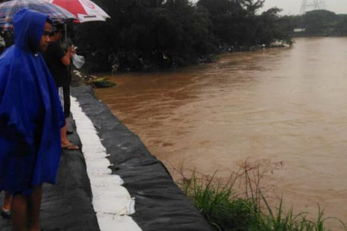 Warga RW013 Perumahan Pondok Mitra Lestari mengamati peningkatan TMA Kali Bekasi dari atas tanggul darurat saat terjadi situasi siaga 1 banjir, Sabtu (9/2/2020). (ANTARA/Andi Firdaus)