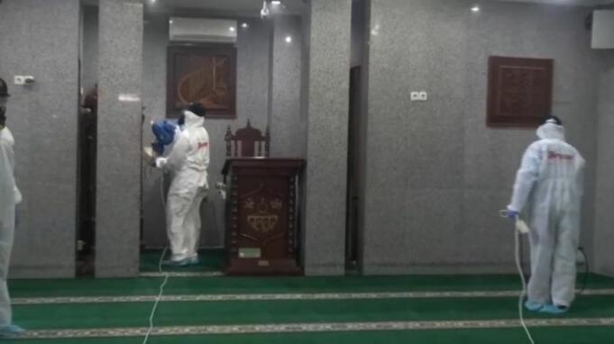 Petugas berpakaian alat pelindung diri lengkap melakukan penyemprotan cairan disinfektan di Masjid Nurul Hidayah, Kebayoran Baru, Jakarta Selatan, Minggu