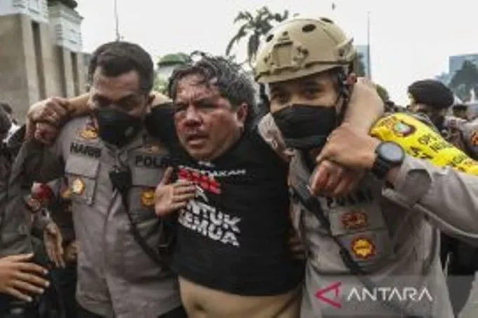 Pegiat media sosial yang juga dosen FISIP UI Ade Armando (tengah) dievakuasi petugas kepolisian seusai dipukuli demonstran pada aksi unjuk rasa di depan Gedung DPR/MPR/DPD RI, Jakarta, Senin (11/4/2022). ANTARA