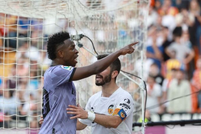 Pemain Real Madrid Vinicius Jr. menunjuk ke arah bangku penonton setelah diduga mendapat kekerasan verbal pada laga lanjutan Liga Spanyol melawan Valencia di Mastella Stadium, Valencia. (21/5/2023) (AFP/JOSE JORDAN)