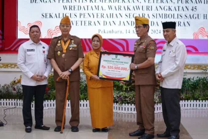 Asisten I Sekretariat Daerah Provinsi Riau, Zulkifli Syukur saat menyerahkan sagu hati secara simbolis kepada veteran disaksikan Ketua Legiun Veteran Republik Indonesia (LVRI) Provinsi Riau, M. Toyyib di Gedung Balai Serindit, Pekanbaru, Rabu(14/08/2024).