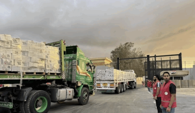 Arsip Foto - Staf Bulan Sabit Merah Mesir berdiri di dekat truk-truk pengangkut bantuan kemanusiaan saat memasuki Jalur Gaza dari sisi Mesir di perbatasan Rafah, Palestina, Minggu (12/10/2025). (ANTARA/Xinhua/Ali Mostafa/aa.)