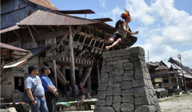 Pelompat batu melompati tumpukan batu setinggi 2,1 meter untuk difoto bersama para turis mengunjungi desa cagar budaya nasional Bawomataluo, Kecamatan Fanayama, Kabupaten Nias Selatan, Sumatera Utara, Sabtu (9/3/2019). Hombo (lompat) batu dalam bahasa suku Nias merupakan salah satu ciri khas budaya dari Nias Selatan yang berasal dari tradisi latihan perang pada masa kerajaan. ANTARA FOTO/Septianda Perdana
