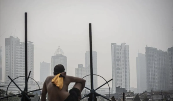 Ilustrasi - Seorang warga berjemur dengan latar belakang gedung bertingkat tersamar kabut polusi udara di Jakarta. ANTARA FOTO/Aprillio Akbar/rwa/aa.